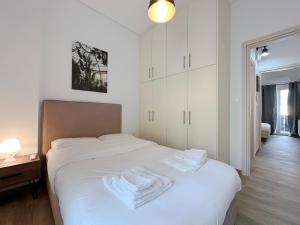 um quarto com uma cama branca e toalhas em Santa Barbara C1 Cityscape 68sqm apt in Nea Smirni em Atenas
