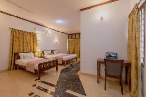 a bedroom with two beds and a desk and a television at Villa 9C by Revkeys in Bangalore