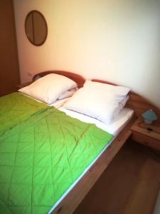 ein Bett mit einer grünen Decke und 2 Kissen in der Unterkunft Apartments Dragi - with pool in Nin