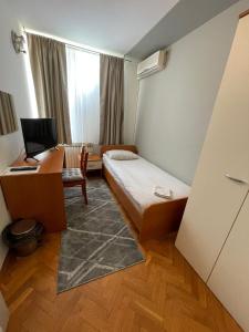 a room with a bed and a desk with a computer at Perla Inn in Osijek