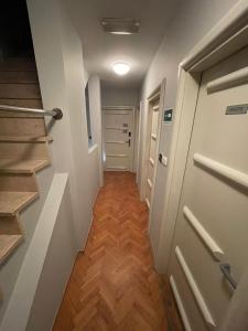 a hallway with a door and wooden floors and stairs at Perla Inn in Osijek