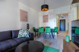 a living room with a couch and a table and green chairs at Club Panorama Lakeside Apartman in Alsóörs