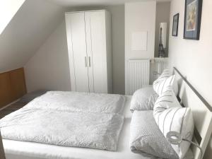 a white bedroom with a bed and a white cabinet at am Rossmarkt Alzey in Alzey