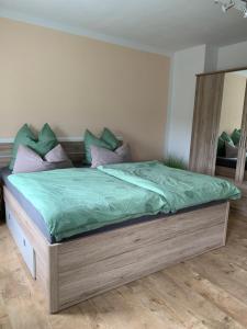 1 dormitorio con 1 cama grande con sábanas y almohadas verdes en Ferienwohnung Neubert, en Zschorlau