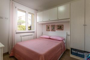 a bedroom with a bed with pink sheets and a window at Casa Pineta in Follonica
