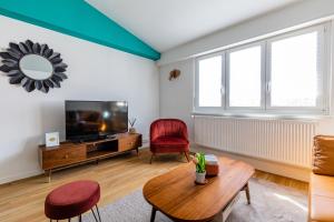 een woonkamer met een tv en een tafel bij Appart Premium aux Portes de Strasbourg avec Parking Privé in Schiltigheim