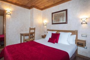 Un dormitorio con una cama grande con una manta roja. en Apartaments Els Llacs, en Bordes d´Envalira