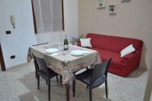 a living room with a table and a red couch at Casa Levante in Augusta