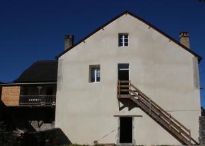 une maison blanche avec un escalier sur le côté dans l'établissement GITE DU MOULIN, à Arudy