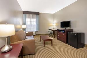 a hotel room with a couch and a television at La Quinta by Wyndham Houston IAH Bush Intl Airport E in Humble