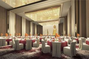 um salão de banquetes com mesas brancas e cadeiras brancas em Wyndham Baise Resort em Baise