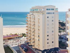 a tall white building with a beach in the background at Apartment Rocha Varandas Atlantis in Portimão
