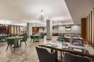a dining room with tables and green chairs at Wyndham Garden Baku in Baku
