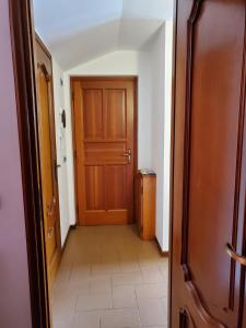 un couloir avec une porte en bois et du carrelage. dans l'établissement Mansarda Via Chanoux, à Saint-Vincent