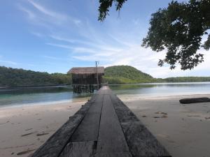a dock on a beach with a house on it at Meos Ambower Homestay Raja Ampat in Fam