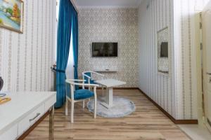 een kamer met een tafel en een blauwe stoel bij Muxlis Hotel in Tasjkent