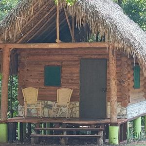 a cabin with two chairs and a thatch roof at Room in Cabin - Cabins Sierraverde Huasteca Potosina Green Cabin in Damían Carmona