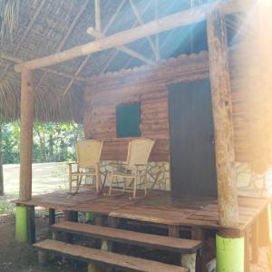a porch of a log cabin with chairs and a table at Room in Cabin - Cabins Sierraverde Huasteca Potosina Green Cabin in Damían Carmona