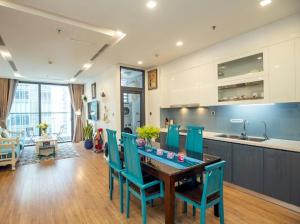 uma cozinha com uma mesa e cadeiras azuis num quarto em Lilyhome - Service Apartments of Vinhomes Metropolis near Lotte em Hanói