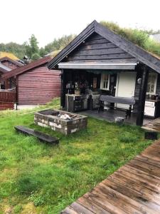 a house with a grill and a picnic table in a yard at Nydelig hytte på Kvamskogen, nær Hardangerfjorden in Kvam