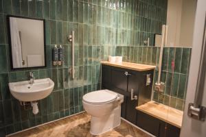 Baño de azulejos verdes con aseo y lavamanos en Cat & Lion Country Pub and Hotel en Warrington