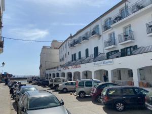 um parque de estacionamento com carros estacionados em frente a um edifício em Hostal Marina Cadaqués em Cadaqués