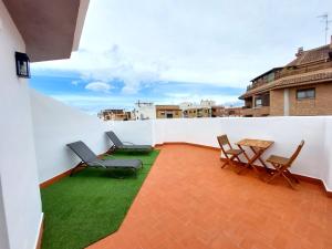 Un balcón con sillas y una mesa en una pared blanca. en Habitaciones Barra89, en Valencia