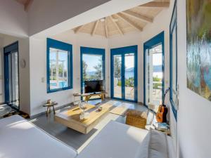 een woonkamer met blauwe ramen en een bank bij Villa Saphora Sea Front Villa in Évyiros