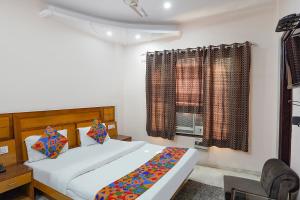 um quarto com uma cama e uma janela com cortinas em FabHotel De Gold em Nova Deli
