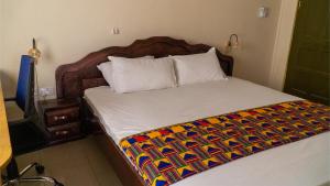 ein Schlafzimmer mit einem Bett mit einer bunten Decke darauf in der Unterkunft Sign of Silence Hostel in Kumasi