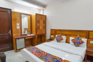 1 dormitorio con 2 camas, escritorio y espejo en FabHotel De Gold en Nueva Delhi