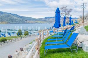 a row of blue chairs with umbrellas and a lake at Dock Holiday with Carriage House #134 in Chelan