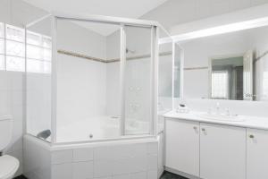 a white bathroom with a shower and a sink at Elizabethan Lodge in Melbourne