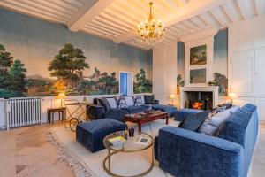 ein Wohnzimmer mit blauen Sofas und einem Kamin in der Unterkunft Le Presbytère - demeure d'exception historique in Biéville-en-Auge