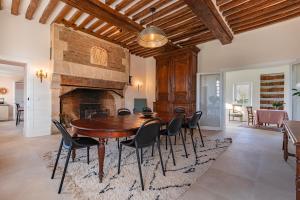 a dining room with a table and chairs and a fireplace at Le Presbytère - demeure d'exception historique in Biéville-en-Auge
