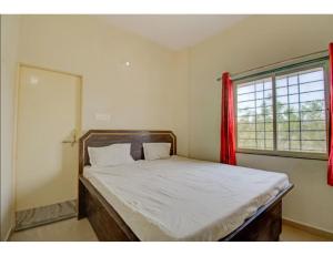 1 cama en un dormitorio con ventana roja en Hotel Chandrajyoti, Deoghar, en Deoghar