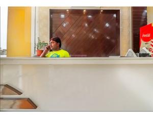 un hombre hablando en un celular delante de un espejo en Hotel Chandrajyoti, Deoghar, en Deoghar