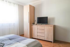 a bedroom with a bed and a tv on a wooden cabinet at Nadmorska Strzecha in Smołdziński Las