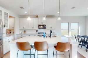 una cocina con armarios blancos y una barra con sillas en Clear Lake Shores en Seabrook