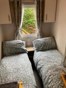 2 camas en una habitación pequeña con ventana en 173A Woodland Way, en Porthmadog