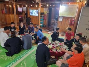 Hoàng Quân Homestay في Ba Be18: مجموعة من الناس يجلسون حول طاولة يأكلون الطعام