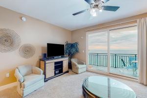 a living room with a tv and a glass table at Sterling Breeze 1705 in Panama City Beach