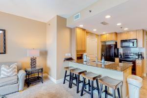 a kitchen with a bar with stools and a couch at Sterling Breeze 1705 in Panama City Beach