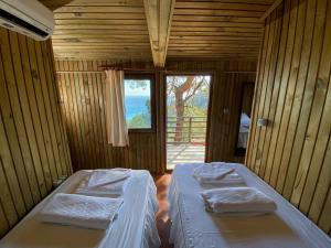two beds in a room with a view of the ocean at Tree Houses Hotel in Fethiye