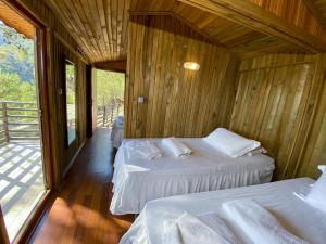 two beds in a room with wooden walls at Tree Houses Hotel in Fethiye