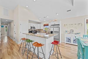 a kitchen with white cabinets and bar stools at Killin' Time in Kill Devil Hills