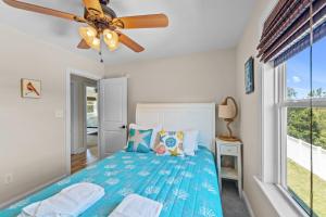 a bedroom with a blue bed and a ceiling fan at Killin' Time in Kill Devil Hills