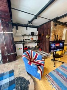 ein Wohnzimmer mit einem blauen Sessel und einem Fernseher in der Unterkunft Стильная студия на Арбате золотой квадрат пересечение Абылай хана - Жибек Жолы in Almaty