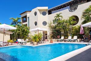 a swimming pool with chairs and umbrellas next to a building at Hotel Don Andres in Sosúa