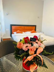 a vase of flowers on a table in a bedroom at Orange House Constanta in Constanţa